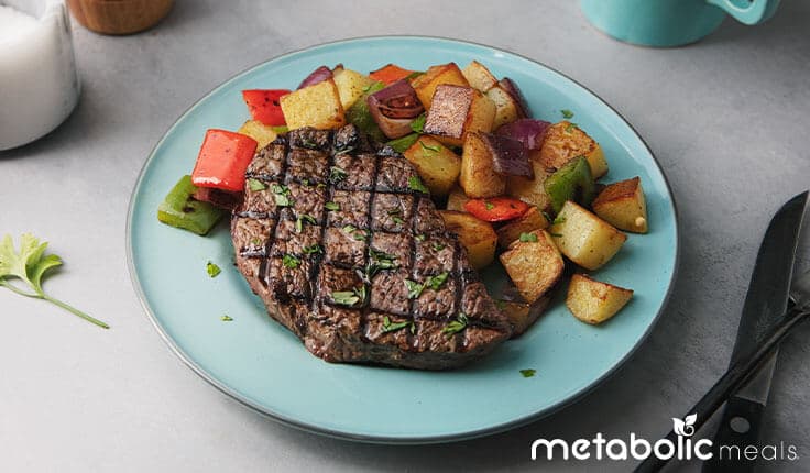 Grass-fed top steak and roasted vegetable meal on table.